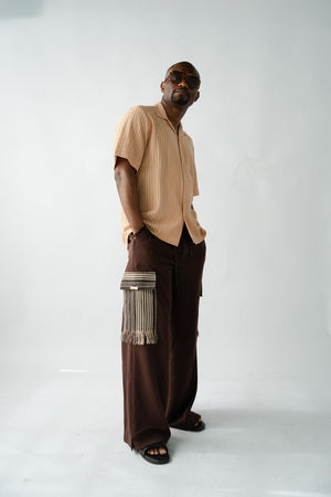 African designer brown wide-leg trousers with artisan Aso Oke detailing, premium fabric texture and modern luxury styling.
