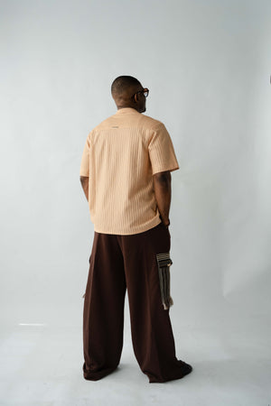 Brown textured wide-leg trousers with oversized silhouette, drawstring waist and traditional Aso Oke cargo pockets.