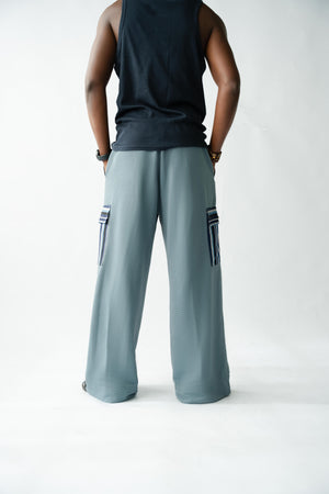 Luxury pale blue men's wide-leg trousers with artisan Aso Oke cargo pocket and premium textured fabric.