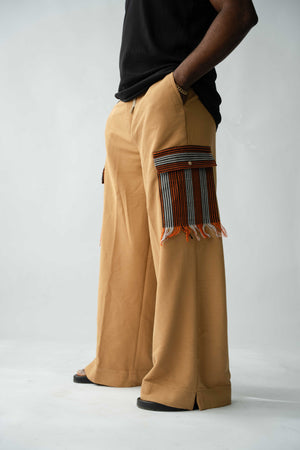 Luxury brown wide-leg cargo trousers for men featuring handcrafted Aso Oke pockets, premium textured fabric, drawstring waist and contemporary African-inspired design. This designer statement piece blends traditional craftsmanship with modern menswear styling.