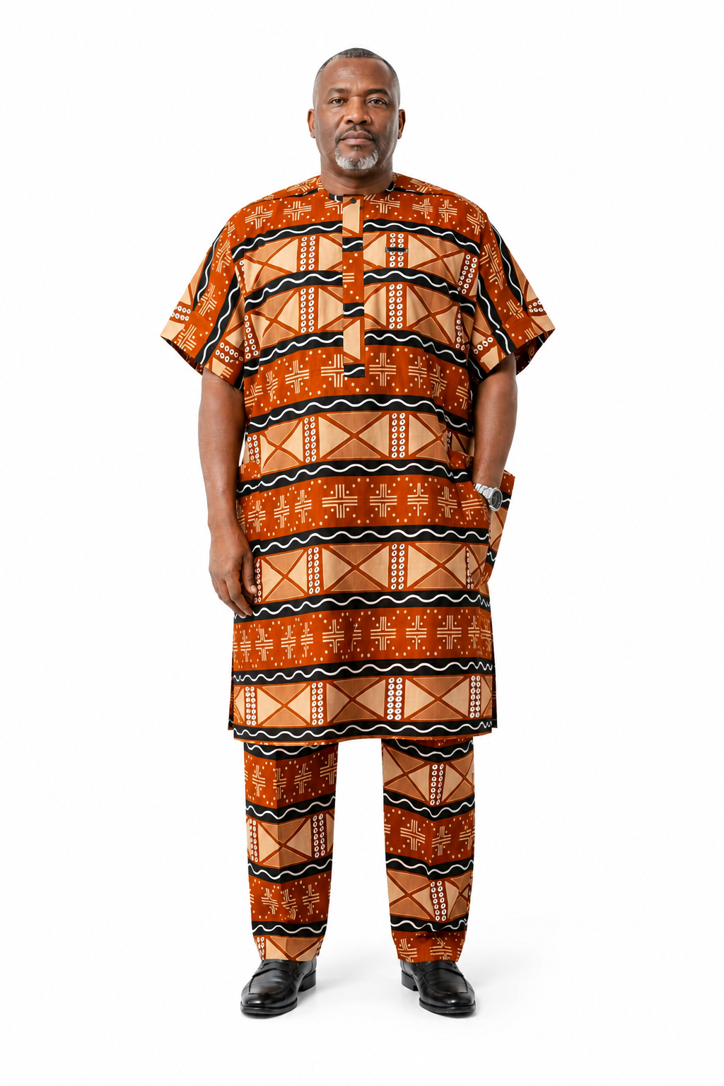 A man modeling a matching short-sleeve button-up shirt and trousers set in a vibrant orange, brown, and black African wax print (Ankara) pattern, photographed against a solid white background.