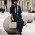 Men's black kaftan set styled with traditional beads and fila cap