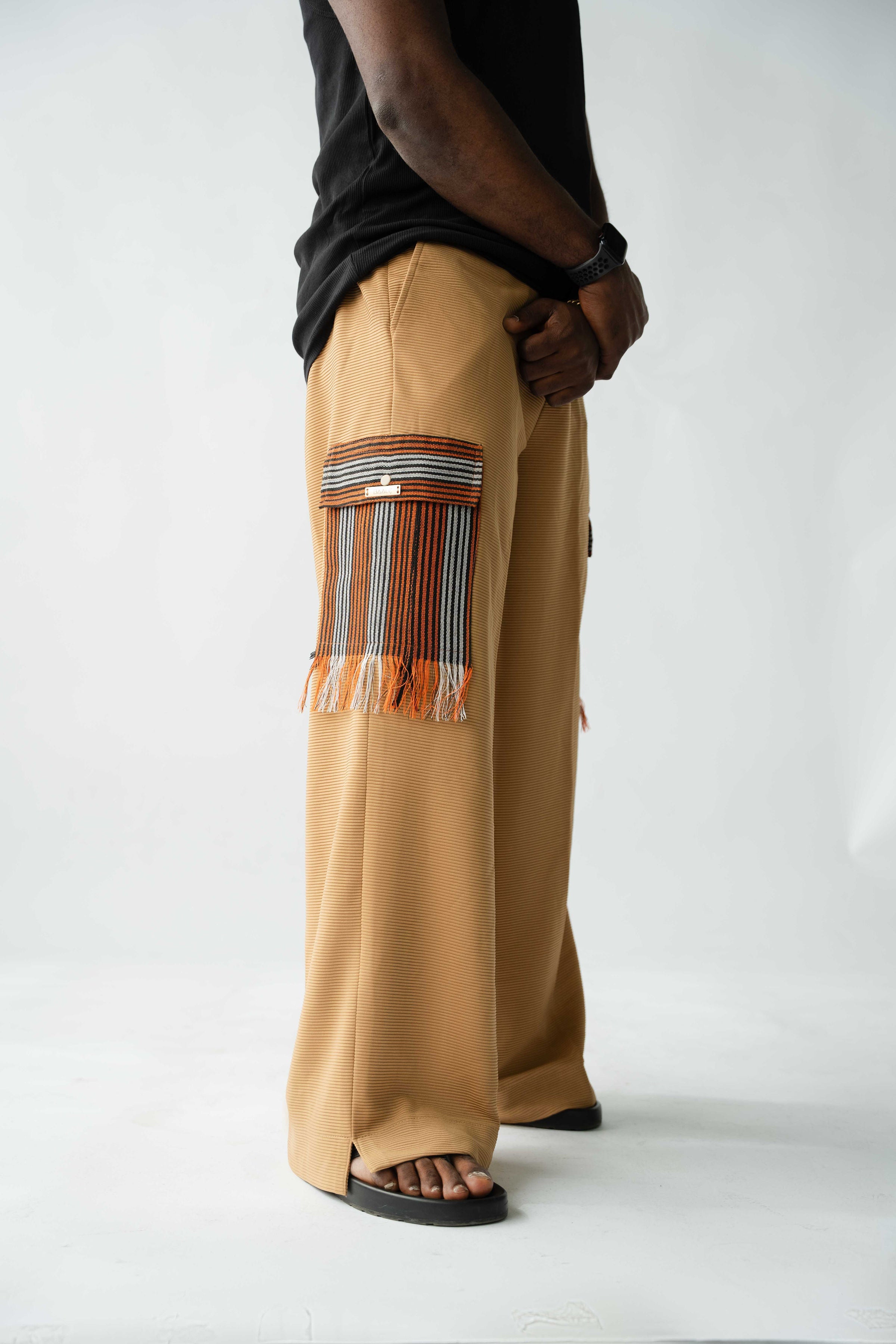 Luxury brown wide-leg cargo trousers for men featuring handcrafted Aso Oke pockets, premium textured fabric, drawstring waist and contemporary African-inspired design. This designer statement piece blends traditional craftsmanship with modern menswear styling.
