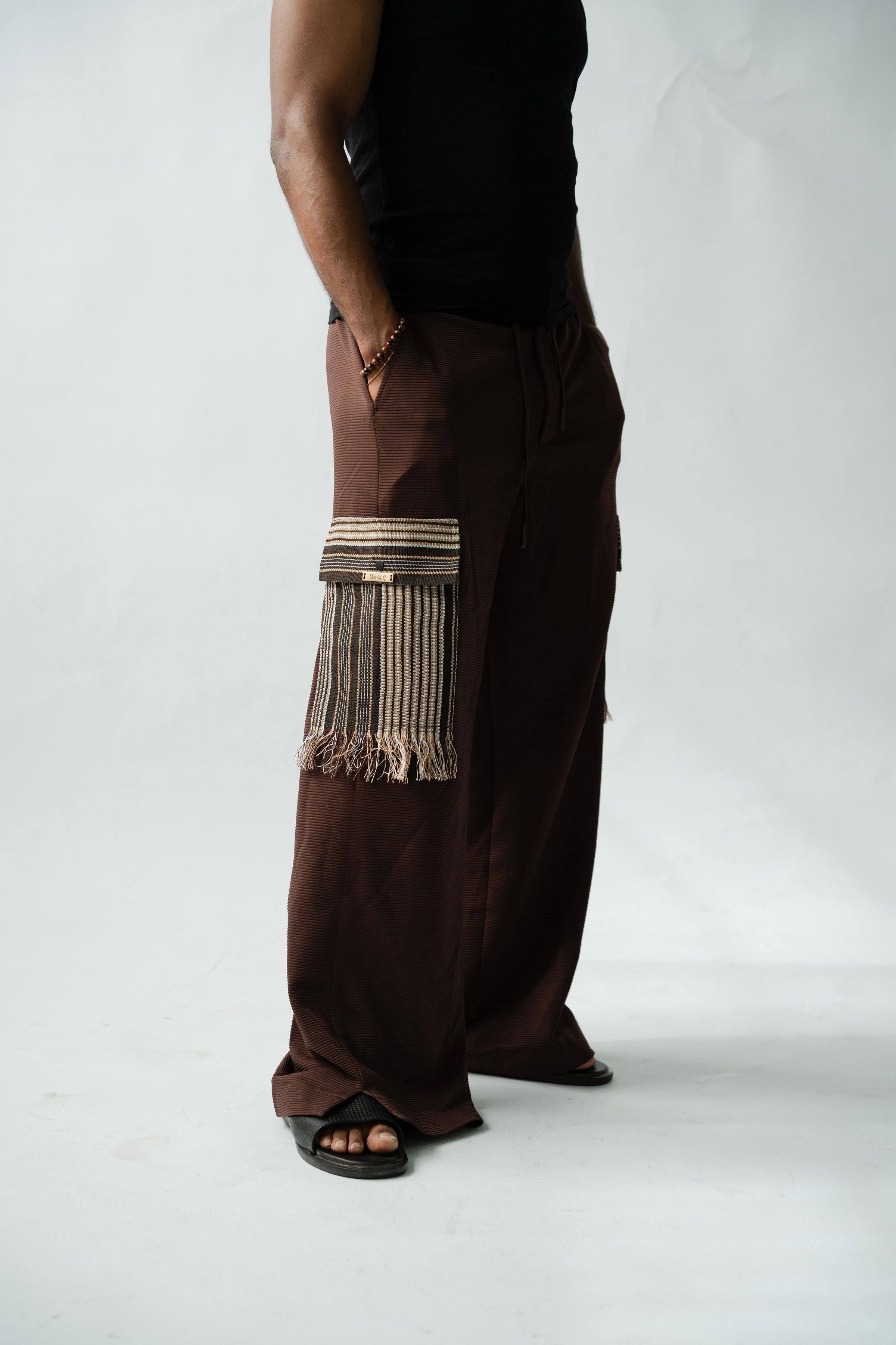 Premium African luxury cargo pants in rich brown fabric with handcrafted striped Aso Oke pocket accents.