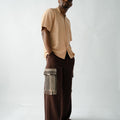African designer brown wide-leg trousers with artisan Aso Oke detailing, premium fabric texture and modern luxury styling.