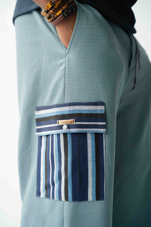 Luxury pale blue wide-leg cargo trousers for men featuring handcrafted blue Aso Oke cargo pockets, premium textured fabric, drawstring waist and contemporary African-inspired design. Designed in London for modern statement menswear.