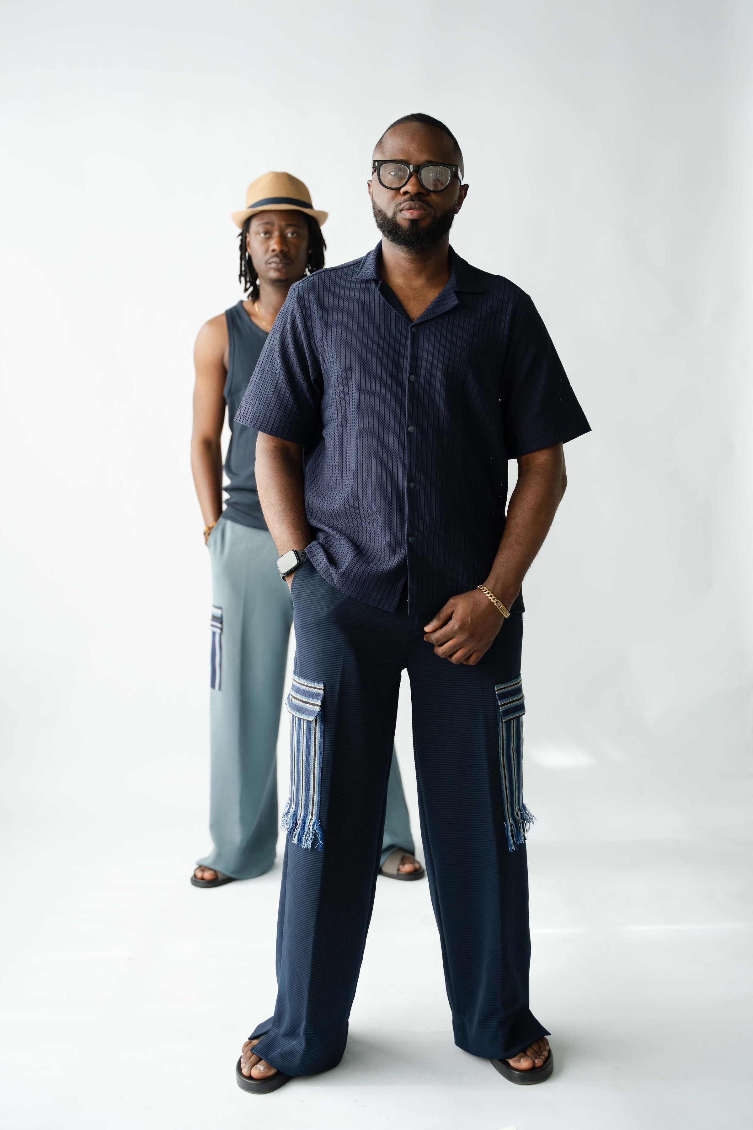 Modern African-inspired men's navy cargo trousers with handcrafted Aso Oke pocket detailing and relaxed silhouette
