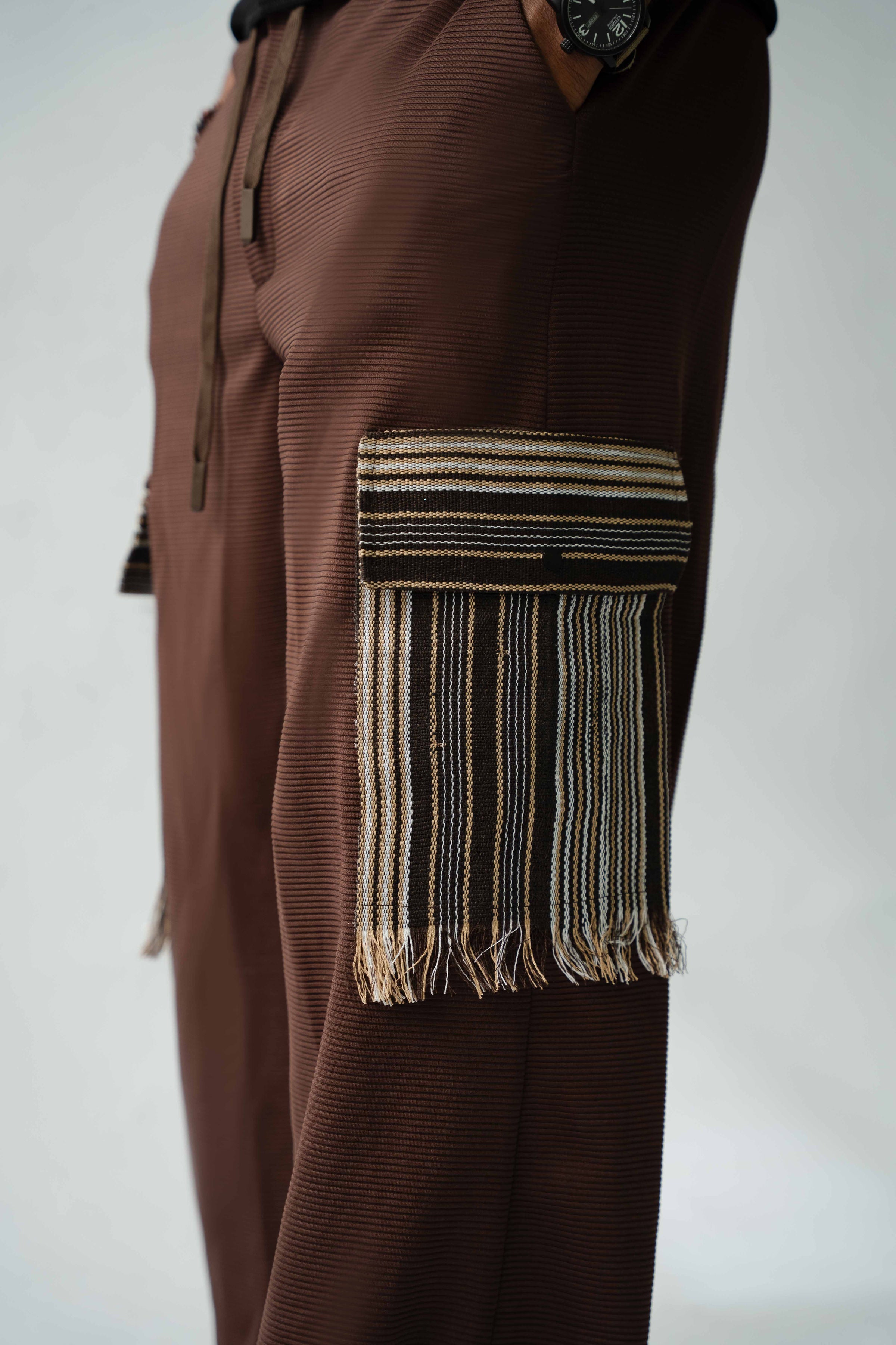 Statement men's brown cargo trousers featuring woven Aso Oke pocket flaps, fringe trim and luxury craftsmanship.
