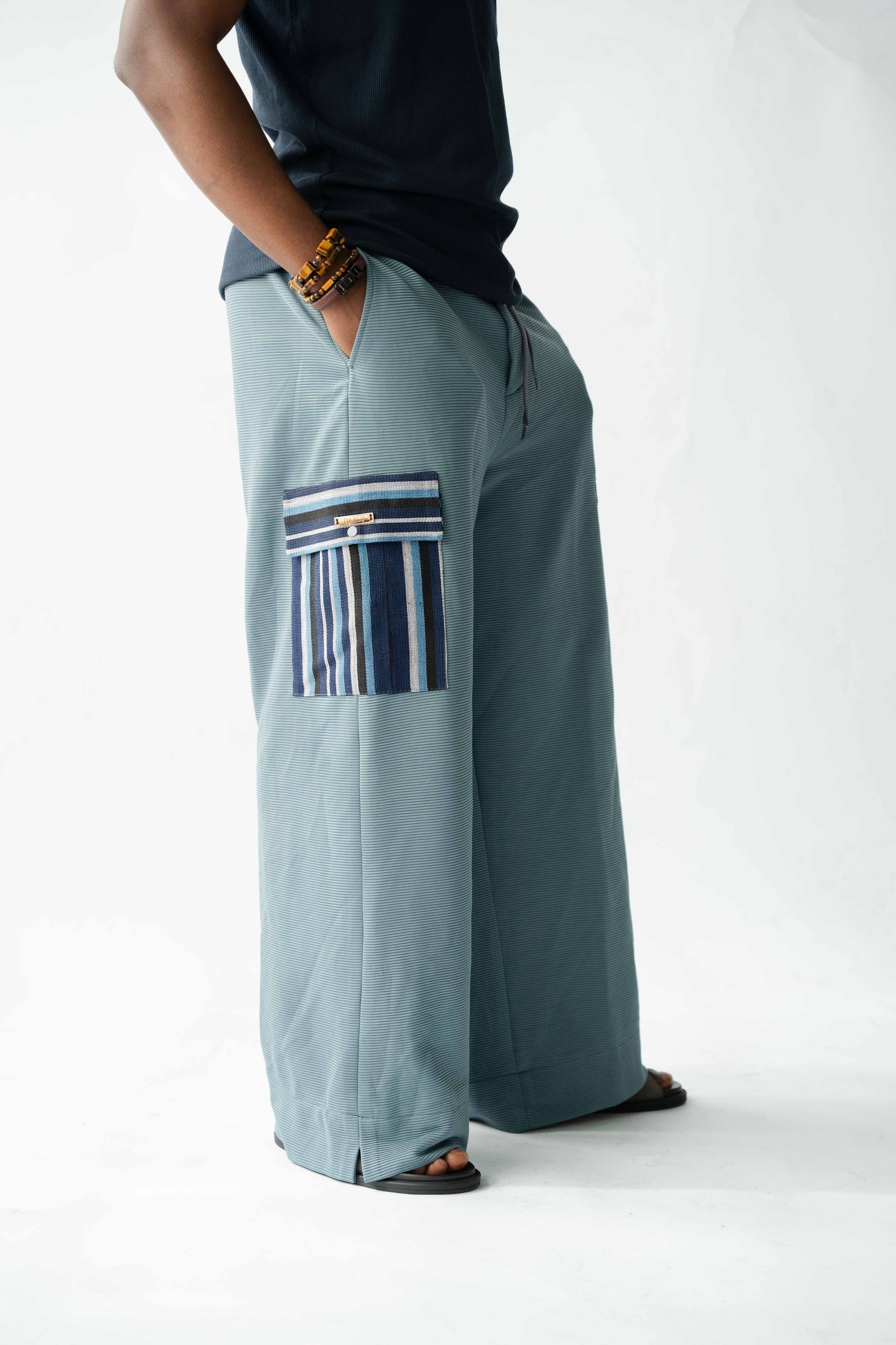 Luxury Pale Blue wide-leg cargo trousers for men featuring handcrafted Aso Oke pockets, premium textured fabric, drawstring waist and contemporary African-inspired design. This designer statement piece blends traditional craftsmanship with modern menswear styling.