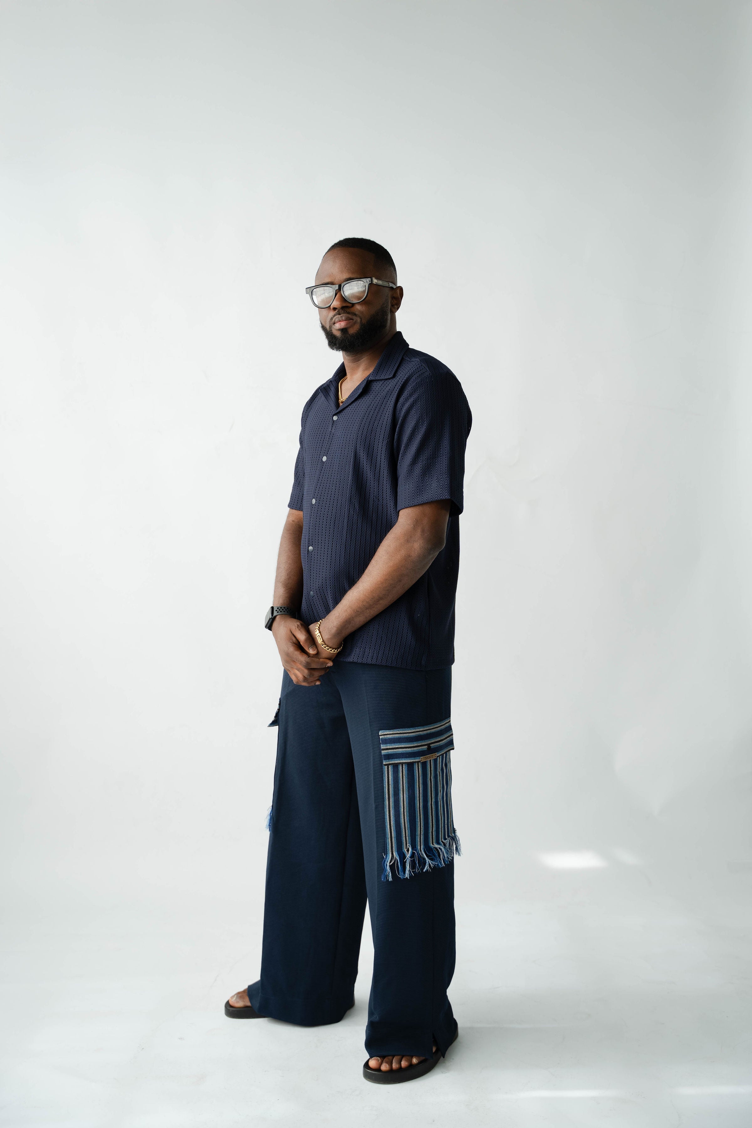 Contemporary African menswear outfit featuring navy resort shirt and Aso Oke cargo trousers